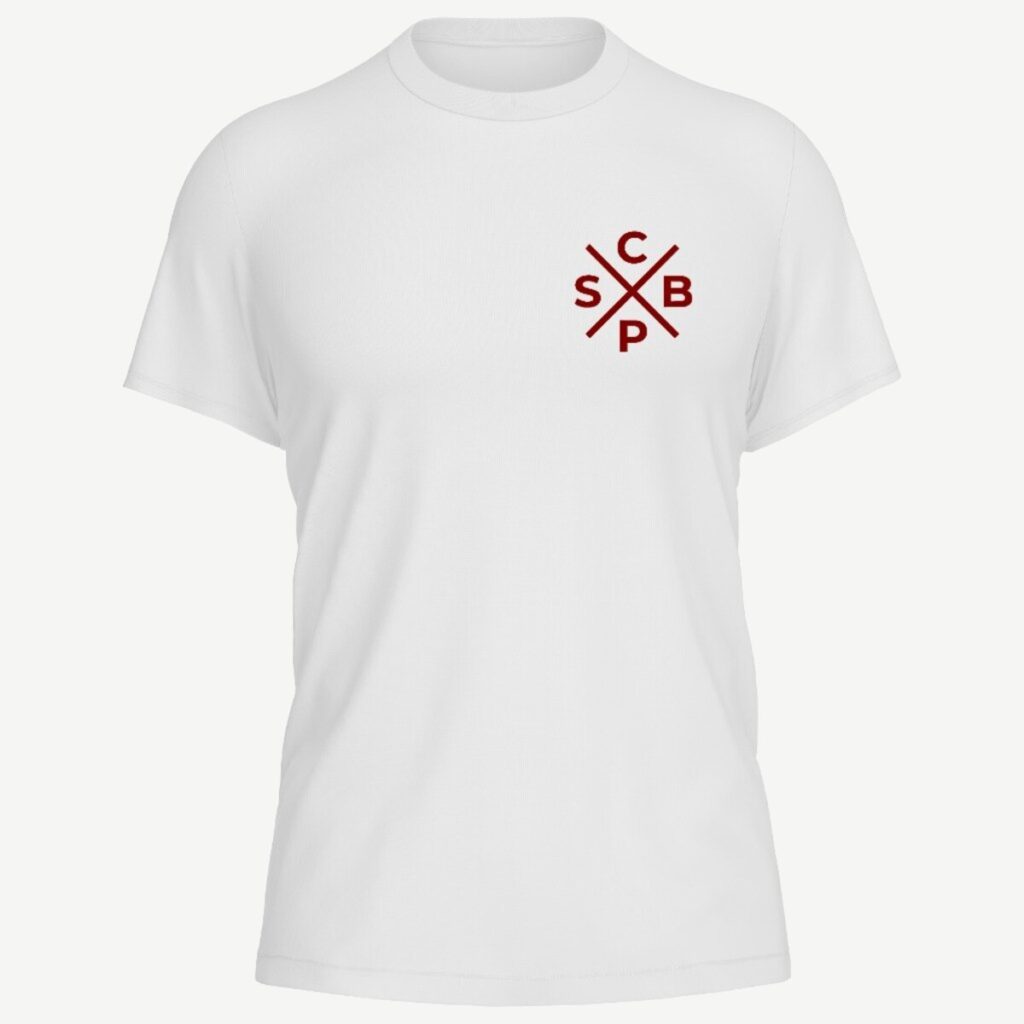 Camiseta branca vista de frente, com o monograma CSPB da cruz de São Bento impresso em tamanho pequeno no lado esquerdo do peito, em vermelho.